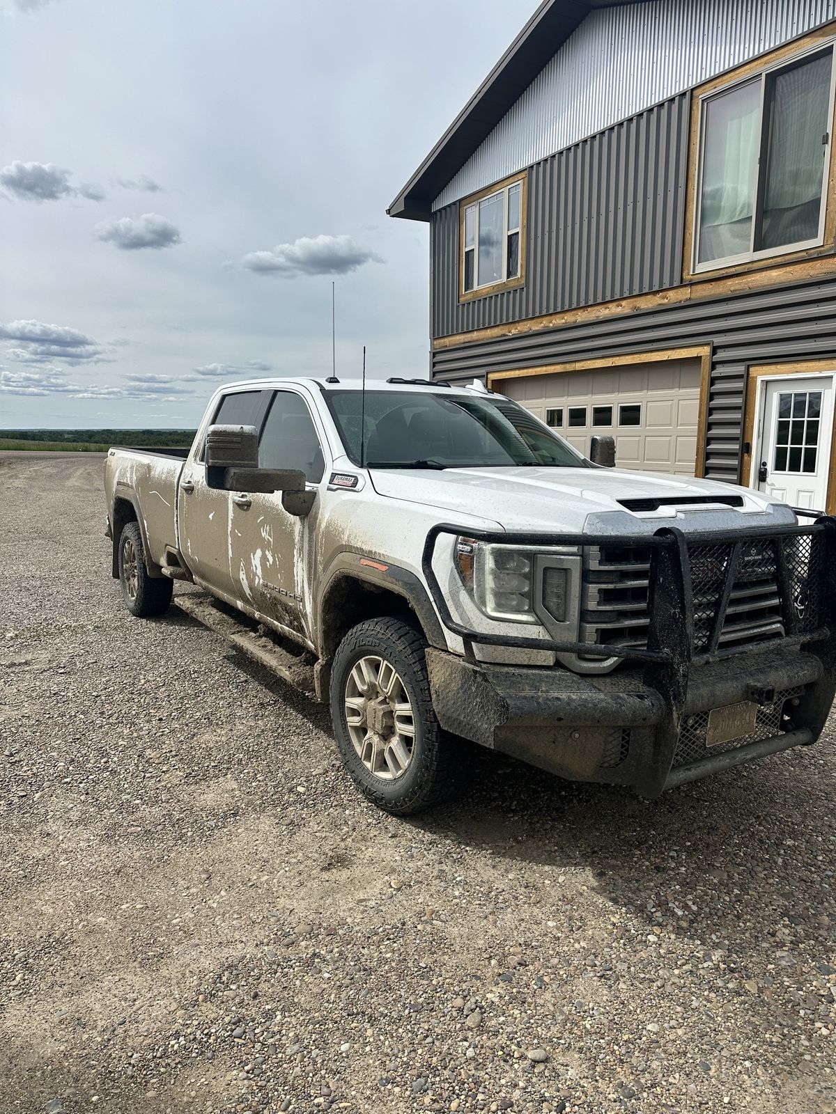 White GMC Sierra 3500 HD packed with Hi-Line farm mud
